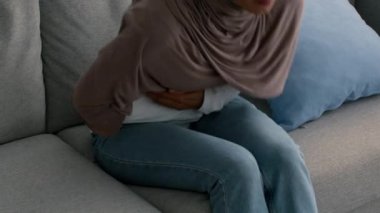 Karın ağrısı çeken tanınmayan Müslüman kadın, kapalı alanda karın ağrısı çekiyor.