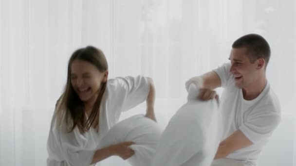 Jonge vrolijke echtgenoten kussen vechten in de slaapkamer, plezier hebben thuis samen — Stockvideo