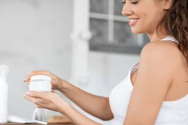 Tanımlanamayan genç bayan yüz kremi kavanozunu banyoda tutuyor.