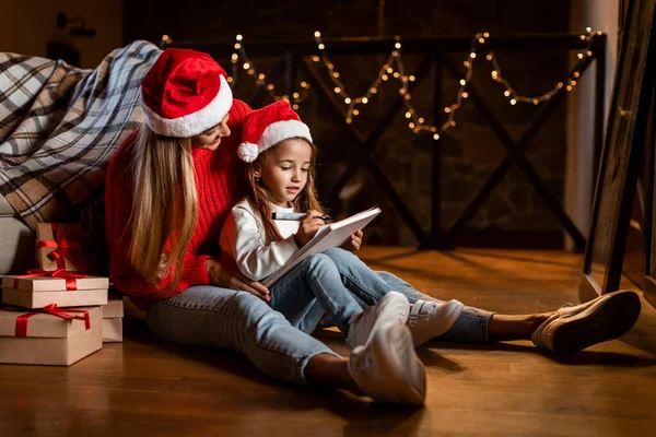 Cute daughter writing letter to Santa with her mother — Stock Photo, Image