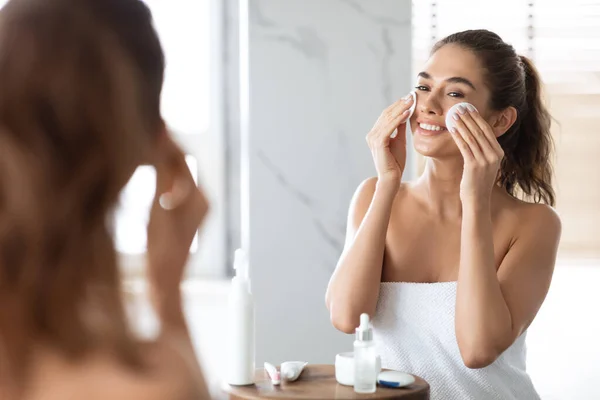 Millennial Lady nettoyage visage en utilisant des tampons de coton dans la salle de bain — Photo