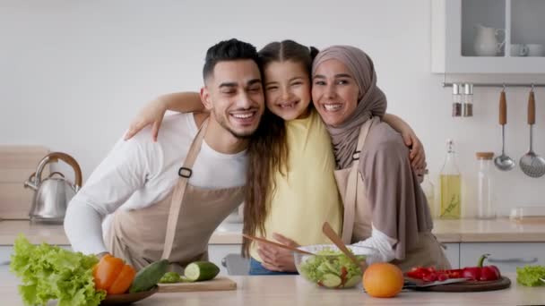 Ευτυχισμένη μουσουλμανική οικογένεια με το κορίτσι παιδί αγκαλιάζει ποζάροντας στην κουζίνα — Αρχείο Βίντεο