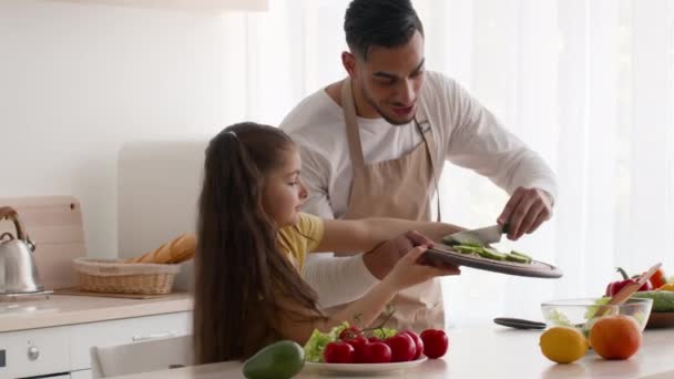 Pai árabe e filha fazendo salada para jantar na cozinha — Vídeo de Stock