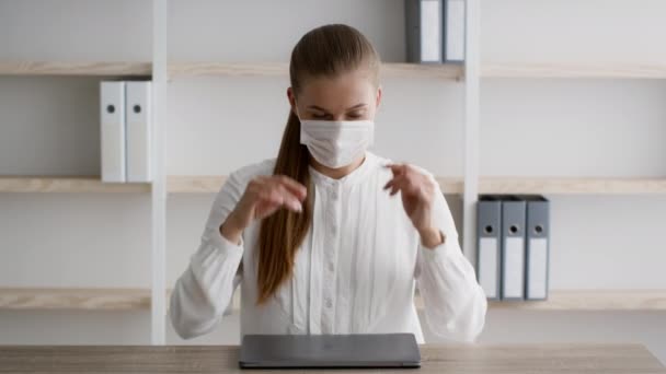 Joven mujer de negocios que cierra el ordenador portátil y se quita la máscara médica en la oficina — Vídeos de Stock