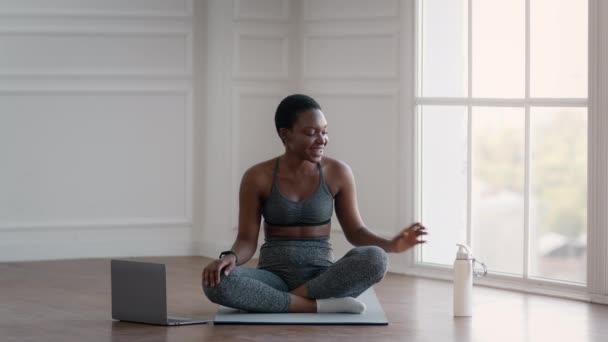 Спортивная черная женщина расслабляется после онлайн-тренировки по фитнесу с ноутбуком, питьевой водой — стоковое видео