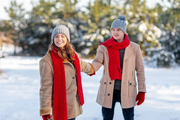 Glückliche junge hübsche Frau zieht an der Hand ihres Freundes und genießt den Schnee — Stockfoto