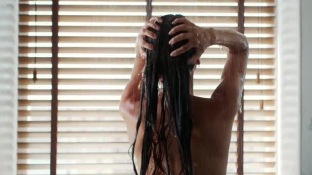 Vista trasera de la mujer lavando el cabello y la cabeza de pie en el baño — Vídeos de Stock