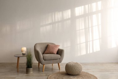 Yastıklı arka koltuk, masada parlak lamba, saksı bitkisi, kanepe ve yerde yuvarlak halı.