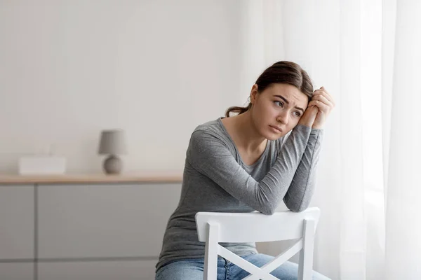 Sad anxious frustrated millennial woman has mental disorder, problems and bad feeling, sits on chair alone — Stock Photo, Image