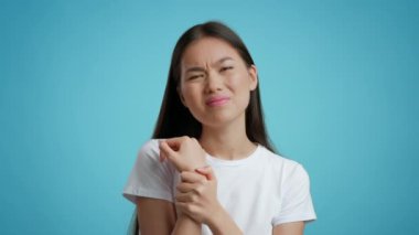 Mutsuz Çinli Kadın Masaj yapıyor Mavi Arkaplanda Bilek Ağrısı