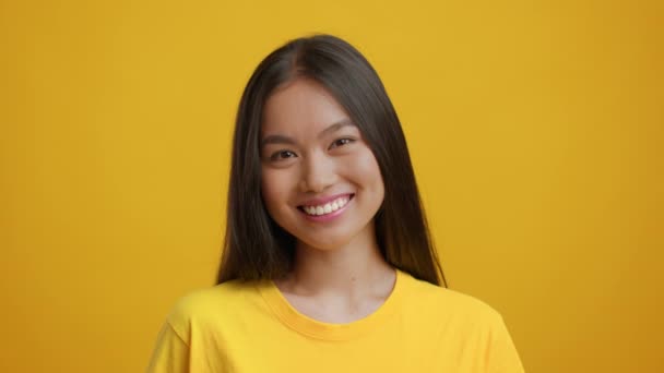 Headshot de muito asiático jovem mulher sorrindo sobre fundo amarelo — Vídeo de Stock