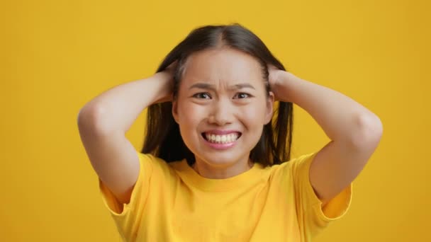 Umutsuz Asyalı Genç Kadın Saçlarını yoluyor, Sarı Arkaplan — Stok video