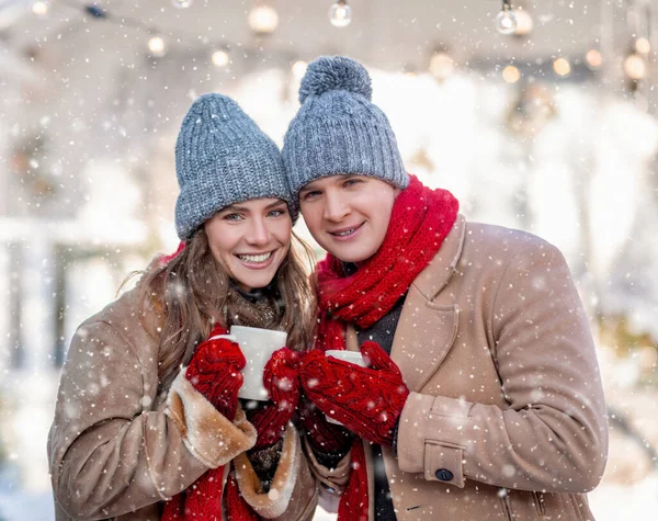 Fröhliches junges Paar genießt Schnee im Hinterhof, trinkt Kaffee — Stockfoto