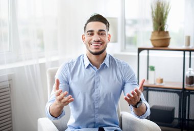 Uzaktan iletişim konsepti. Resmi kıyafetli neşeli bir Arap 'ın ev ofisinden görüntülü görüntüsü.