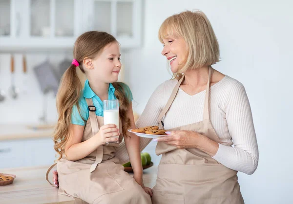 Abuela alimentación linda niña con galletas y leche —  Fotos de Stock