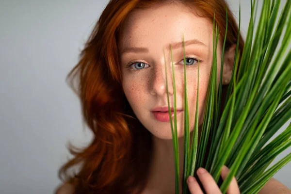 Retrato de menina de cabelos vermelhos olhando para a câmera através da grama, Estúdio — Fotografia de Stock