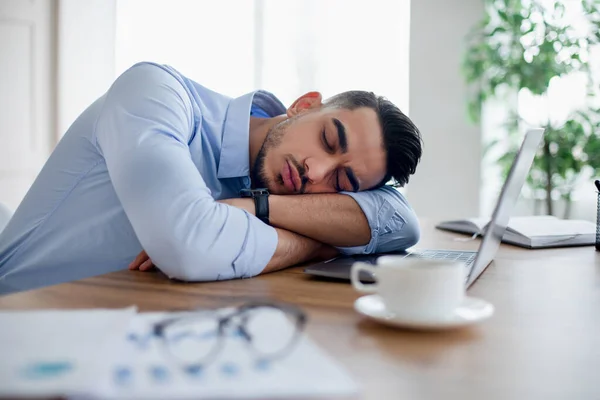 Moe Arabische zakenman slapen op zijn bureau voor laptop, overwerken, zich uitgeput voelen in modern kantoor — Stockfoto