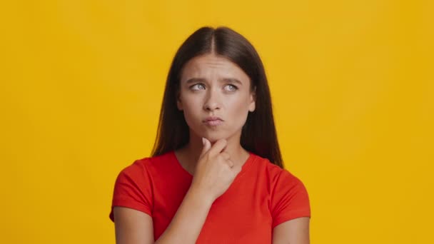 Frau denkt nach und zeigt mit dem Finger nach oben, hat eine Idee, einen gelben Hintergrund — Stockvideo