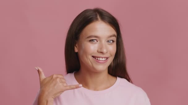 Женщина, указывающая на камеру и кричащая "Позови меня", розовый фон — стоковое видео