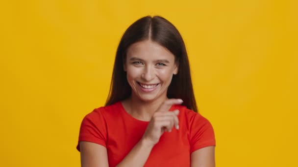 Lady Gesturing Vinger Op Lippen Glimlachen naar de camera, Gele achtergrond — Stockvideo