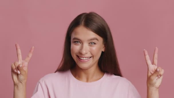 Веселая леди Жест V-знак Поза улыбаясь на камеру, розовый фон — стоковое видео