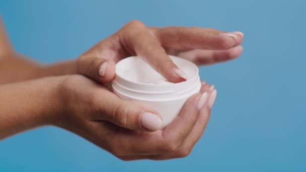 Onherkenbare vrouw houden Moisturizer Cream pot over blauwe achtergrond — Stockvideo