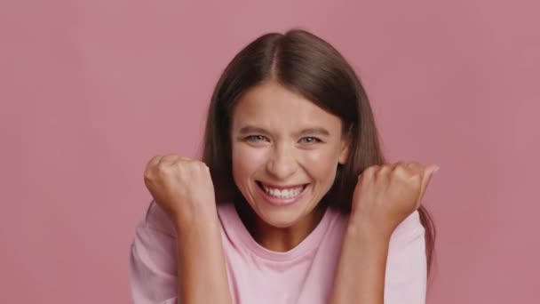 Mujer alegre sacudiendo puños celebrando el éxito sobre fondo rosa — Vídeos de Stock