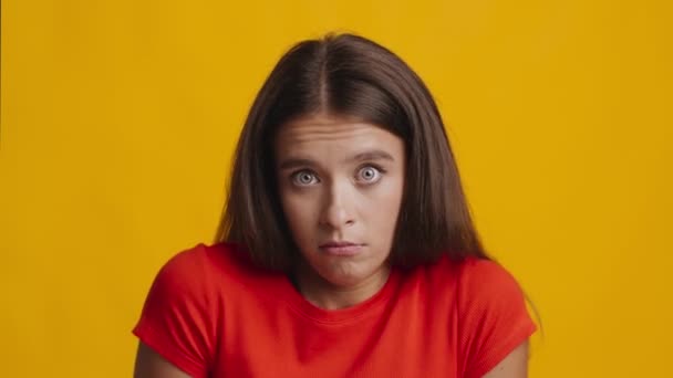 Ahnungslose Frau zuckt mit den Schultern und posiert vor gelbem Studiohintergrund — Stockvideo
