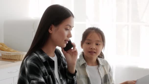忙しいアジア人フリーランスのお母さん携帯電話で話す娘を無視室内 — ストック動画