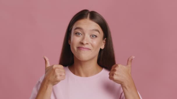 Kvinna Gesturing tummar upp med båda händerna över rosa bakgrund — Stockvideo