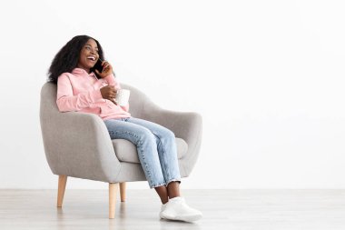 Kahve fincanı olan mutlu siyah kadın telefonda konuşuyor.