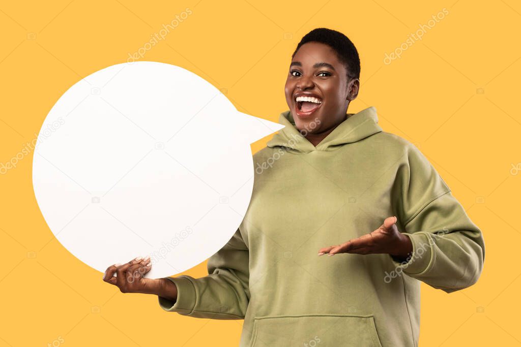 African American Plus-Size Woman Holding Empty Speech Bubble, Yellow Background
