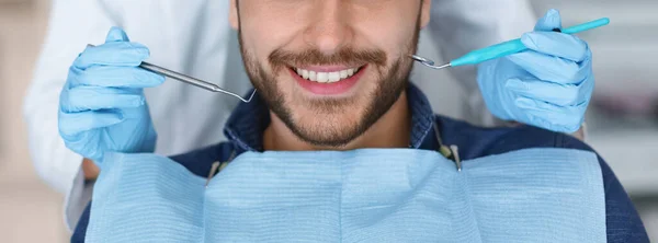 Mosolygós férfi és fogorvos kezek vágása szerszámokkal, panoráma — Stock Fotó