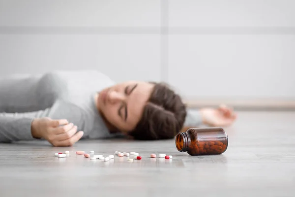 Triste europeo milenial dama inconsciente acostado en el suelo con pastillas dispersas, se suicidó en casa — Foto de Stock