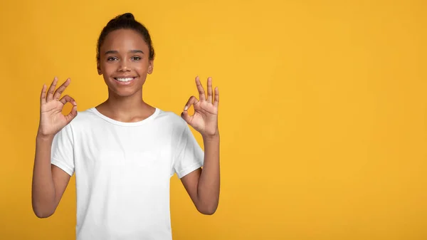 Cheerful glad teenage afro american girl in white t-shirt showing ok sign with hands — Stock Photo, Image