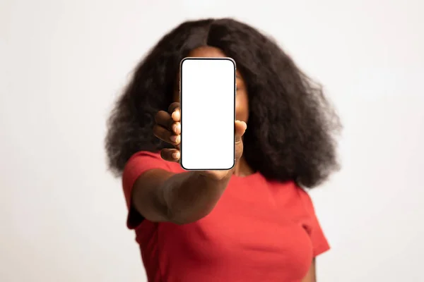 Мобильная реклама. Неузнаваемая афроамериканка, закрывающая лицо пустым смартфоном — стоковое фото