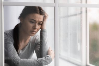 Depresyon, stres ve pencerenin yanında yağmur damlaları olan ruhsal sorunları olan mutsuz üzgün Avrupalı genç bayan.