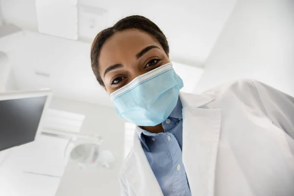 Dama dentista negra inclinada sobre paciente durante el chequeo en clínica dental —  Fotos de Stock