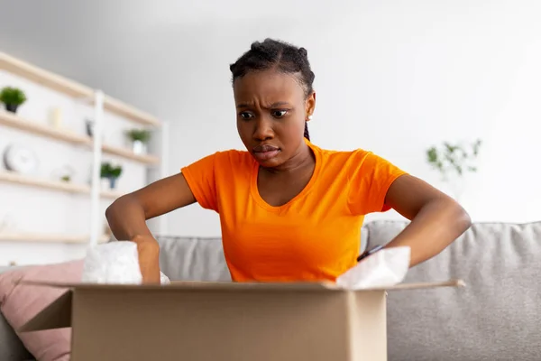 Geschokt Afro vrouw unboxing levering, boos vanwege verzendfout, ontevreden met online shopping service — Stockfoto
