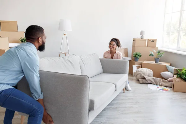 Família afro-americana milenar positiva carrega sofá para novo apartamento com caixas de papelão — Fotografia de Stock