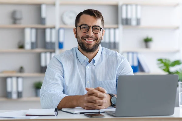 Glücklicher kaukasischer Mann mittleren Alters mit Bart und Brille, der im Büro oder in der Wohnung mit Laptop arbeitet — Stockfoto