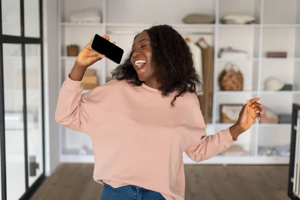 黒人女性の歌は自宅で楽しみを持っているスマートフォンを保持 — ストック写真