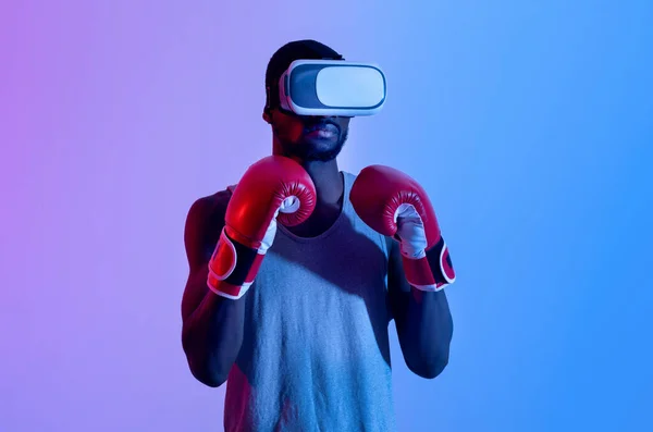Jonge zwarte sportman in VR-headset en bokshandschoenen met virtuele training in neon licht — Stockfoto