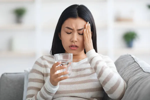 Huvudvärk Begreppet. Sjuk ung asiatisk kvinna lider av migrän hemma — Stockfoto