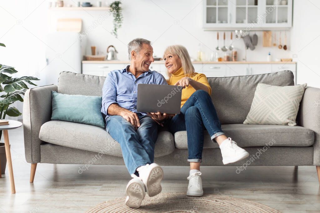 Mature Couple Using Laptop Computer Together Browsing Internet At Home