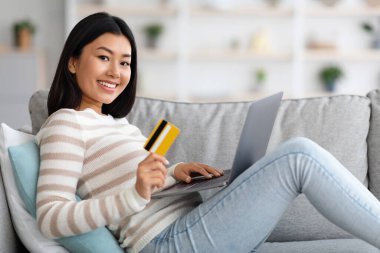 İnternetten alışveriş. Laptop ve kredi kartıyla mutlu Asyalı kadın portresi