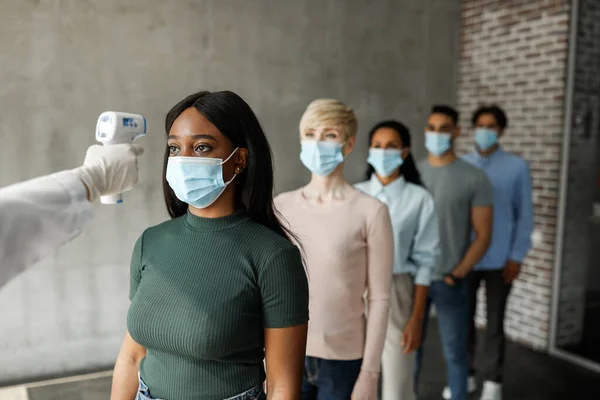 International group of people in face masks checking body temperature — Stock Photo, Image