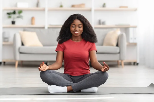 Mujer negra pacífica meditando sola en casa —  Fotos de Stock