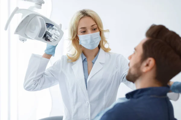 Yüz maskeli kadın dişçi erkek hastayı selamlıyor. — Stok fotoğraf