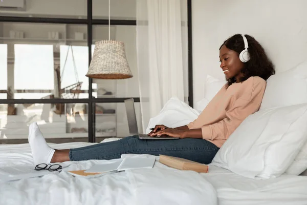 Seitenansicht einer Afroamerikanerin mit Laptop im Schlafzimmer — Stockfoto